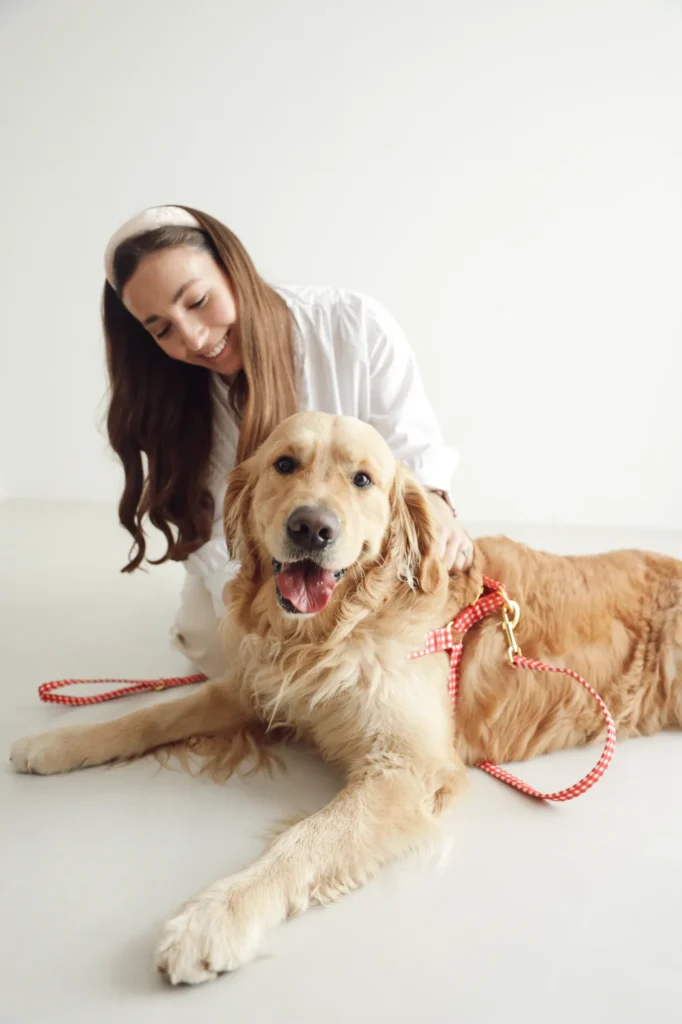 Mujer con un golden retriever que lleva el arnés Vichy rojo y la correa a juego