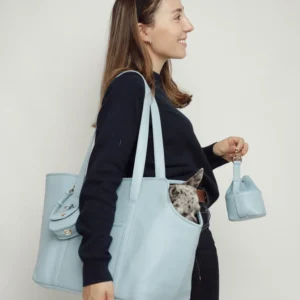 Model carrying the Sky Blue leather dog carrier on the shoulder with a dog inside and the treat bag in hand