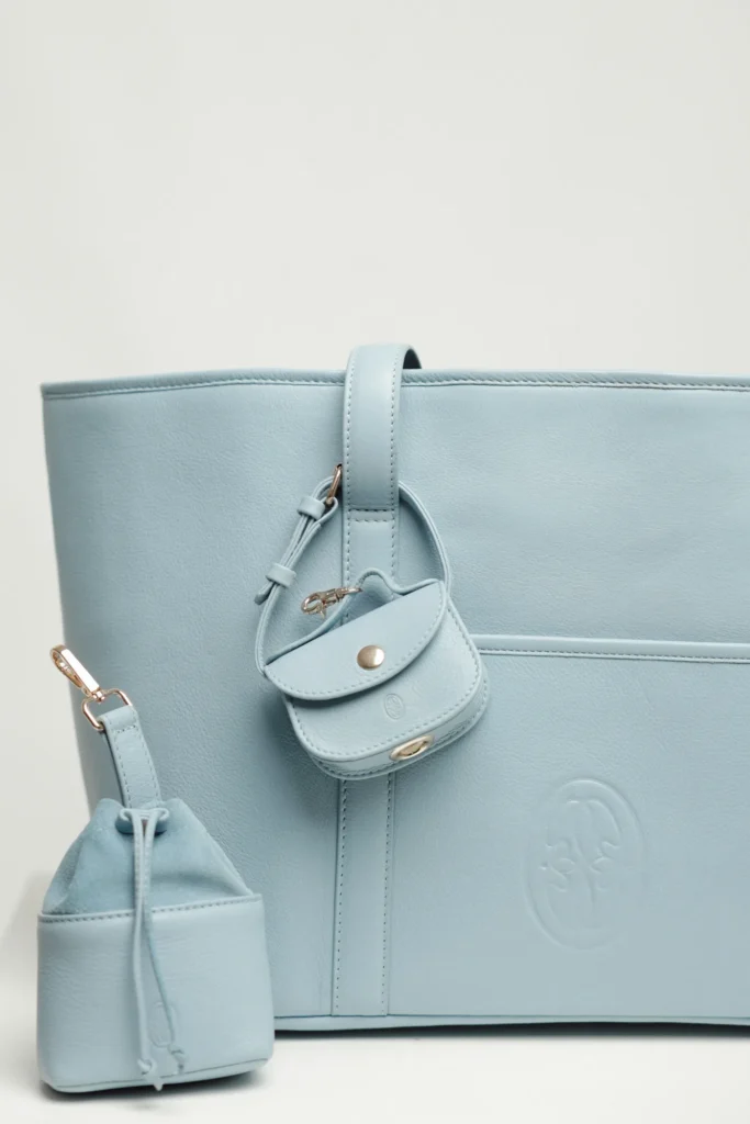 Detail of the Sky Blue leather dog carrier with the poop bag holder on the strap and the treat bag