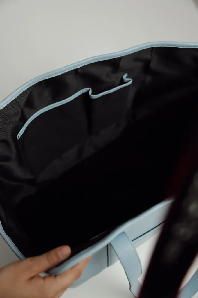 Black lined interior of the Sky Blue leather dog carrier with an inside pocket