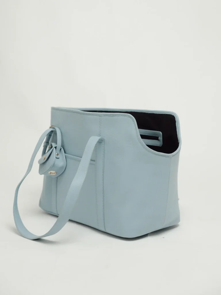 Side view of the Sky Blue leather dog carrier with the poop bag holder clipped to the strap