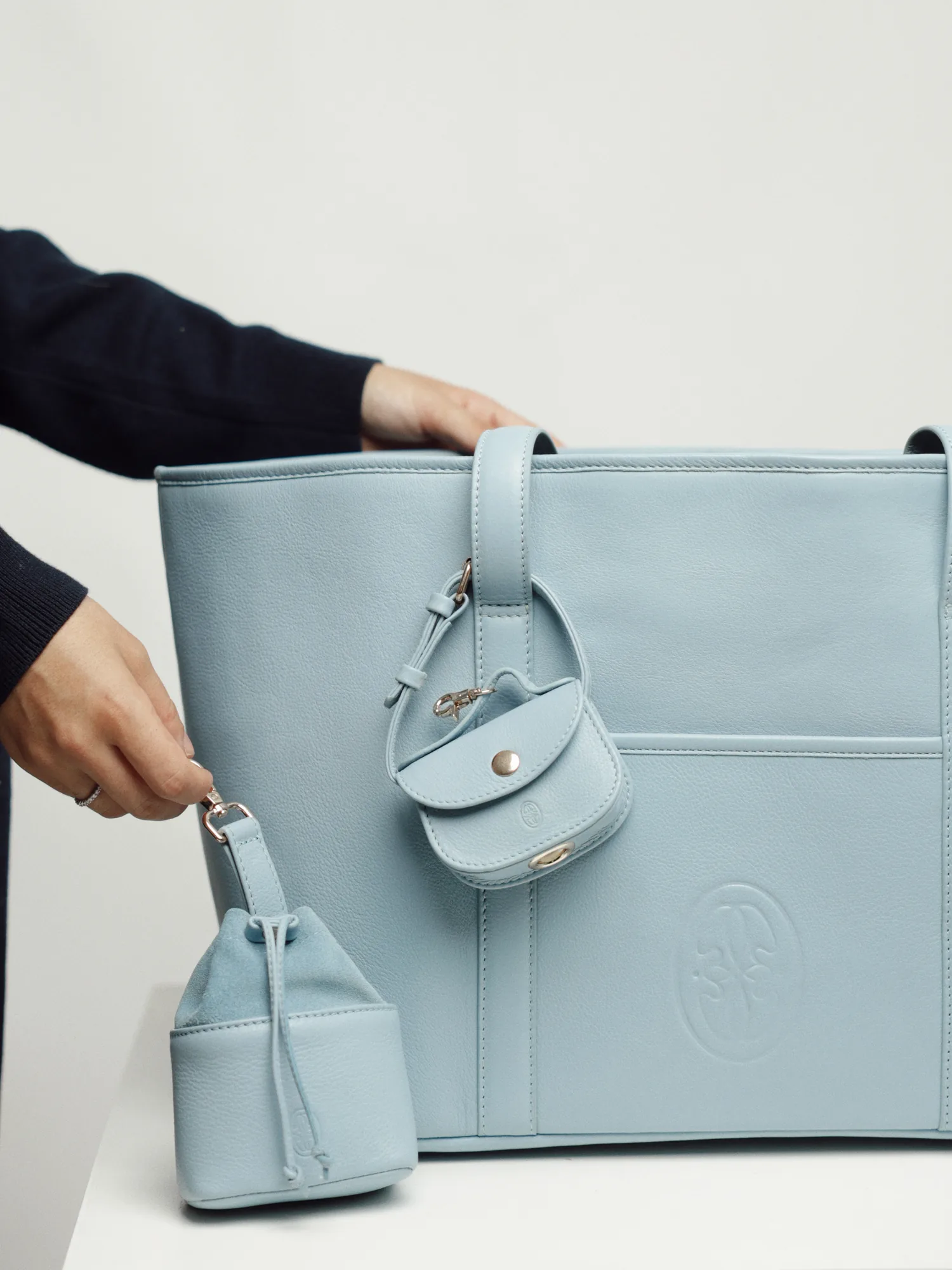 Embossed Oliva logo on the Sky Blue leather dog carrier, with the poop bag holder and treat bag