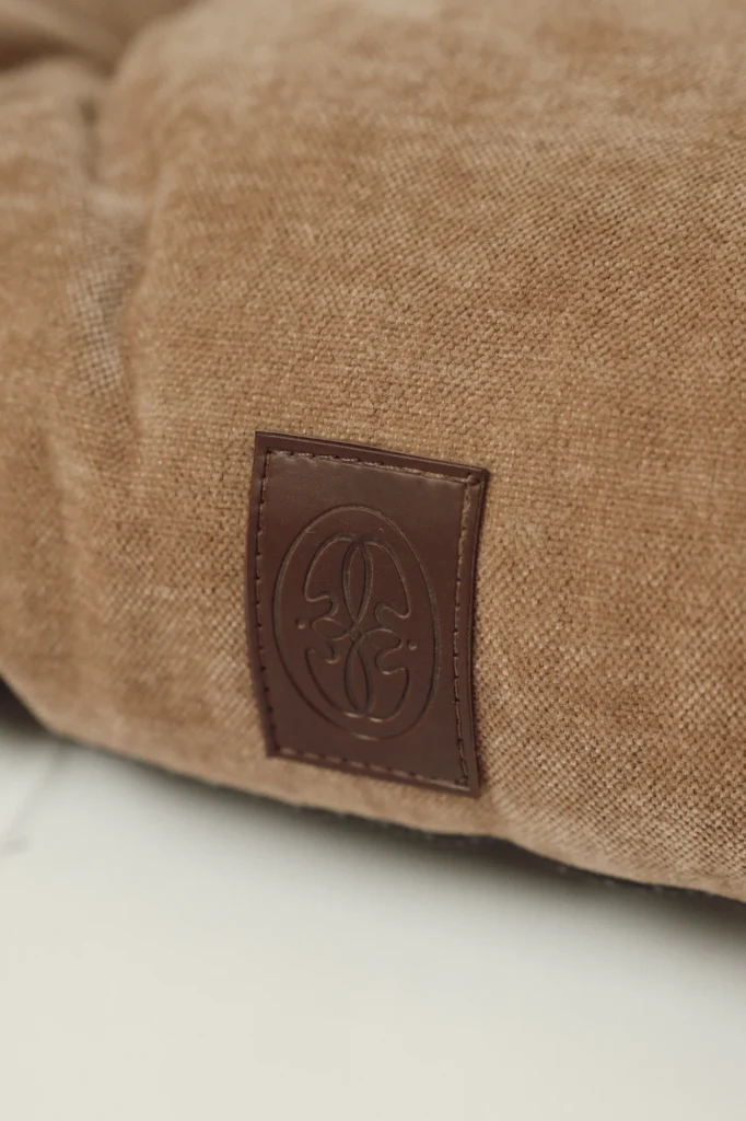 Close-up of the embossed leather Oliva logo on the Atelier dog bed
