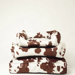 Three Moo dog beds with cow print in sizes S, M and L, stacked