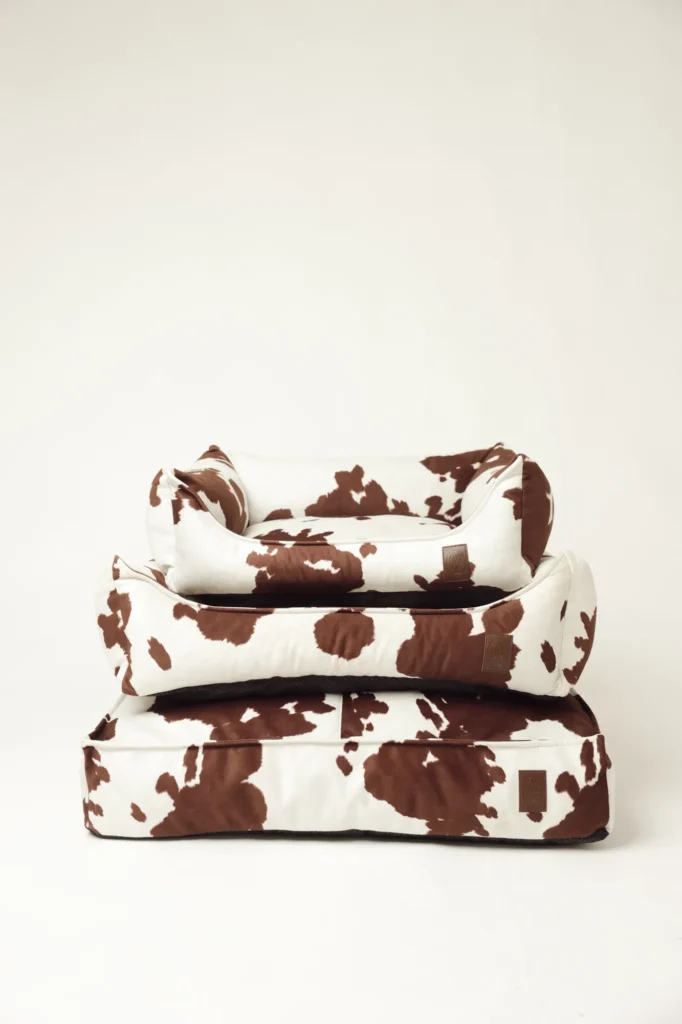 Three Moo dog beds with cow print in sizes S, M and L, stacked