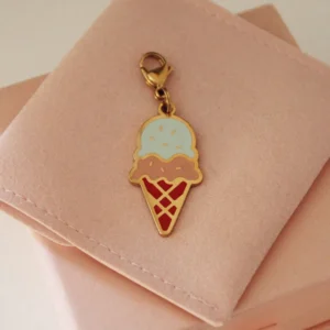 Double-scoop ice cream cone charm in blue and pink with a gold-tone clasp on a pale pink pouch