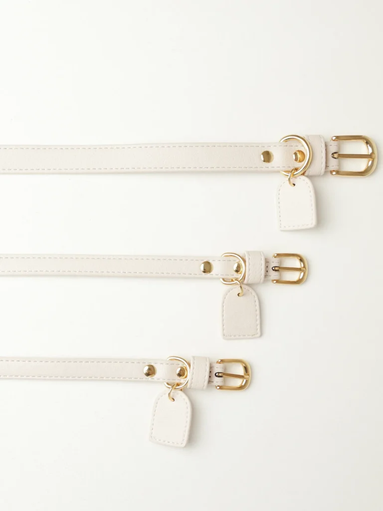 White personalised dog collars in three sizes with gold-tone buckles and leather tags