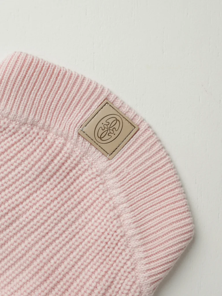 Close-up of the Oliva leather label on the blush pink knit dog jumper
