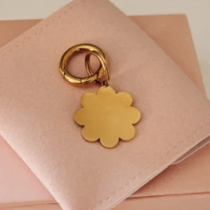 Placa identificativa dorada para perro en forma de flor, personalizada y grabada con láser, con anilla dorada sobre una funda rosa palo