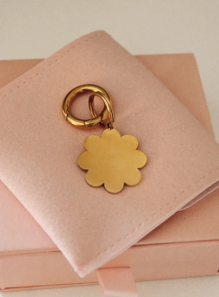 Placa identificativa dorada para perro en forma de flor, personalizada y grabada con láser, con anilla dorada sobre una funda rosa palo
