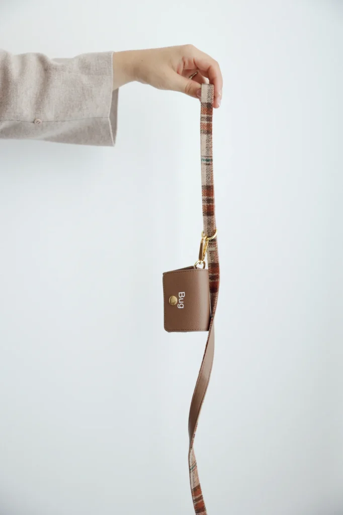 Brown poop bag holder personalised with the name Bug on a tartan lead